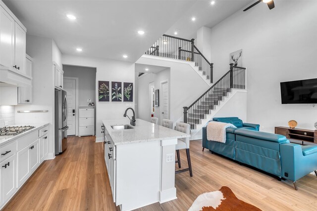 9219 Trimble Landing Dr, Tomball, TX 77375 - kitchen with appliances with stainless steel finishes, a kitchen bar, light wood-style flooring, open floor plan, and recessed lighting