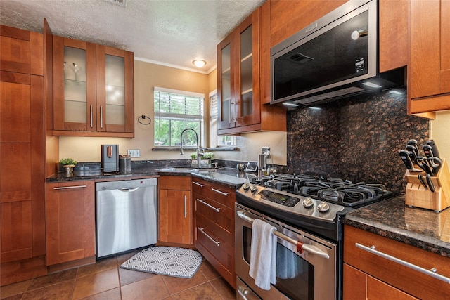 1417 S Heron Dr, Seabrook, TX 77586 - kitchen with appliances with stainless steel finishes, brown cabinetry, crown molding, backsplash, and a textured ceiling