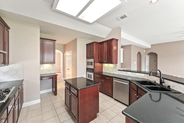 14210 Hansons Creek Ct, Houston, TX 77044 - kitchen with stainless steel appliances, arched walkways, decorative backsplash, light tile patterned floors, and a kitchen island