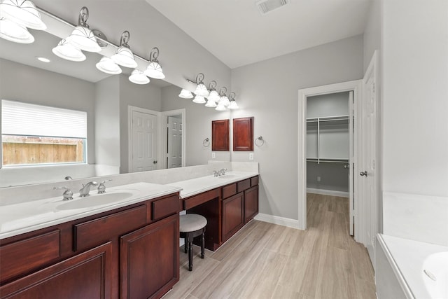 14210 Hansons Creek Ct, Houston, TX 77044 - full bathroom with double vanity, a walk in closet, wood finished floors, and a bathtub