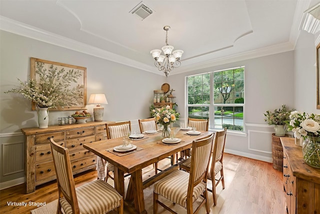 14210 Hansons Creek Ct, Houston, TX 77044 - dining room with a chandelier, light wood-style floors, a wainscoted wall, crown molding, and a decorative wall