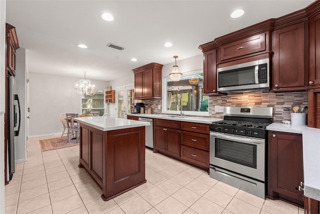 248 S Pathfinders Cir, The Woodlands, TX 77381 - kitchen featuring appliances with stainless steel finishes, decorative backsplash, light countertops, a chandelier, and a center island