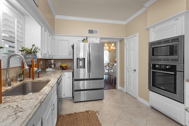 9311 Windrush Dr, Spring, TX 77379 - kitchen with appliances with stainless steel finishes, ornamental molding, a chandelier, white cabinets, and light tile patterned floors