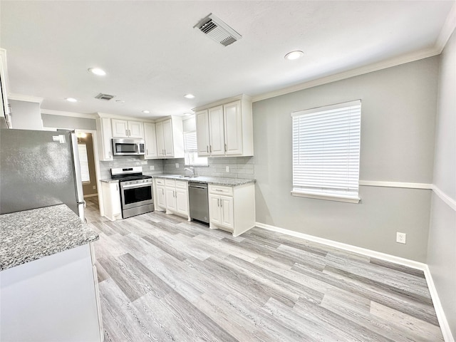 5818 Birchmont Dr, Houston, TX 77092 - kitchen featuring appliances with stainless steel finishes, crown molding, tasteful backsplash, white cabinets, and light wood finished floors