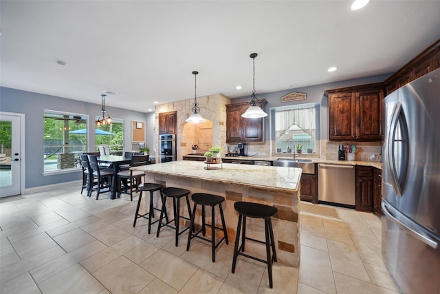 14014 Lakewood Crossing Blvd, Houston, TX 77070 - kitchen featuring appliances with stainless steel finishes, backsplash, a kitchen island, light stone counters, and a breakfast bar