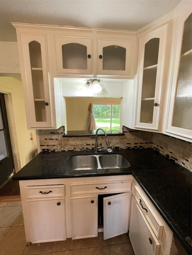 7539 Carothers St, Houston, TX 77028 - kitchen with tasteful backsplash, dark tile patterned floors, glass insert cabinets, and white cabinetry