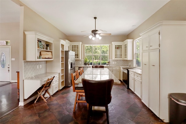 105 Sally Lake Ct, Angleton, TX 77515 - kitchen with stainless steel fridge, ceiling fan, a center island, tasteful backsplash, and glass insert cabinets