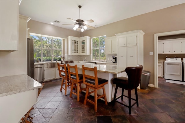105 Sally Lake Ct, Angleton, TX 77515 - kitchen featuring washer / dryer, stone tile flooring, ceiling fan, backsplash, and light stone counters