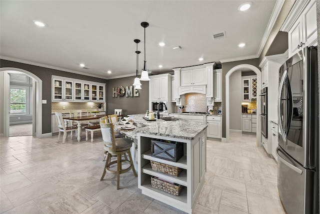 1002 Pleasant Pines Ln, Pinehurst, TX 77362 - kitchen with appliances with stainless steel finishes, arched walkways, open shelves, ornamental molding, and recessed lighting