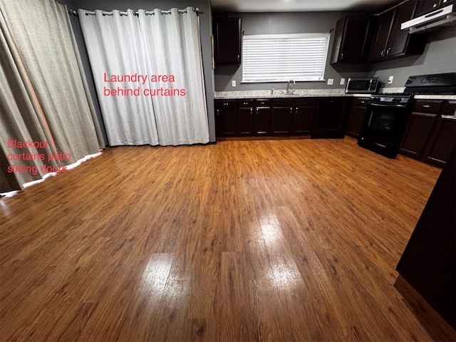 5155 Verdenbruk Dr, Houston, TX 77066 - kitchen with black gas range oven, under cabinet range hood, stainless steel microwave, light wood-style flooring, and light countertops