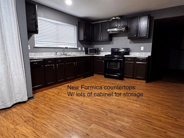 5155 Verdenbruk Dr, Houston, TX 77066 - kitchen featuring black range with gas stovetop, under cabinet range hood, light wood-style floors, stainless steel microwave, and recessed lighting