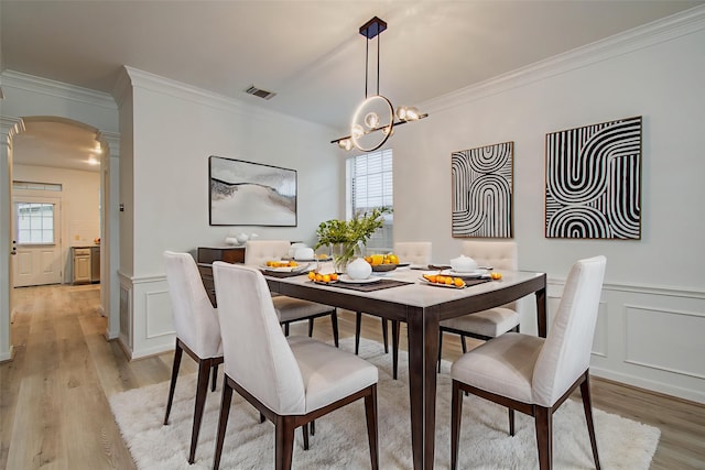 20531 Spring Rose Dr, Katy, TX 77450 - dining room with a decorative wall, arched walkways, crown molding, light wood-type flooring, and ornate columns