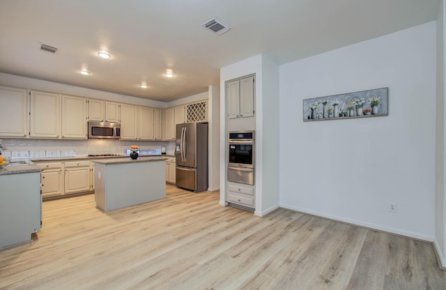 20531 Spring Rose Dr, Katy, TX 77450 - kitchen featuring appliances with stainless steel finishes, a warming drawer, light wood-style flooring, a center island, and decorative backsplash