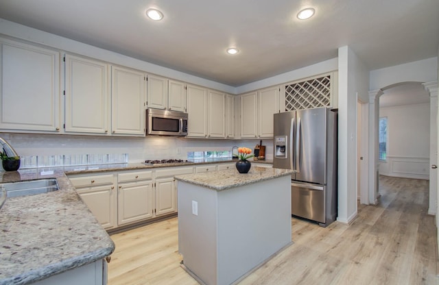 20531 Spring Rose Dr, Katy, TX 77450 - kitchen with stainless steel appliances, arched walkways, light wood finished floors, decorative columns, and recessed lighting
