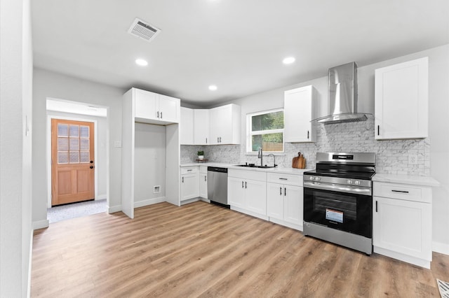 327 E Delz Dr, Houston, TX 77022 - kitchen with stainless steel appliances, wall chimney range hood, backsplash, light countertops, and light wood-style floors