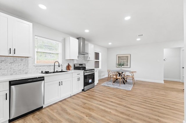 327 E Delz Dr, Houston, TX 77022 - kitchen with appliances with stainless steel finishes, wall chimney range hood, backsplash, light wood-style flooring, and light countertops