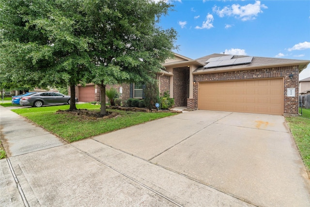8934 Finnery Dr, Tomball, TX 77375 - view of front facade with brick siding, driveway, roof mounted solar panels, a garage, and a front lawn