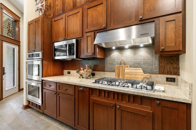 15608 Queen Victoria Ct, Montgomery, TX 77316 - kitchen with extractor fan, stainless steel appliances, tasteful backsplash, and brown cabinetry
