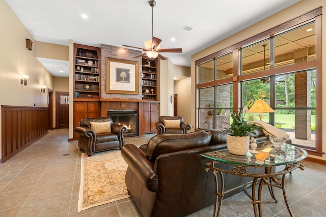 15608 Queen Victoria Ct, Montgomery, TX 77316 - living area featuring a glass covered fireplace, a wainscoted wall, ceiling fan, built in shelves, and recessed lighting