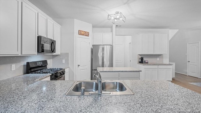 17734 Pensford Way, Tomball, TX 77377 - kitchen with black appliances, tasteful backsplash, wood finished floors, white cabinets, and a textured ceiling