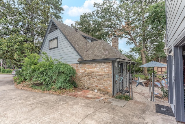 410 Shadywood Cir, Conroe, TX 77304 - view of side of property featuring a gate, a shingled roof, a chimney, and brick siding