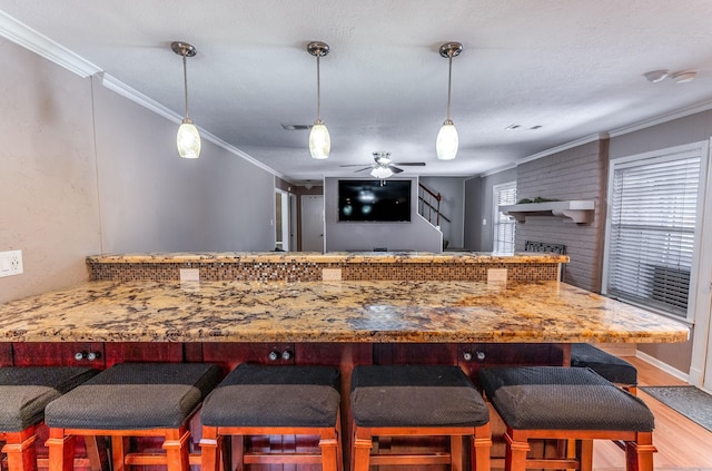 410 Shadywood Cir, Conroe, TX 77304 - kitchen with wood finished floors, ornamental molding, a ceiling fan, decorative light fixtures, and light stone countertops