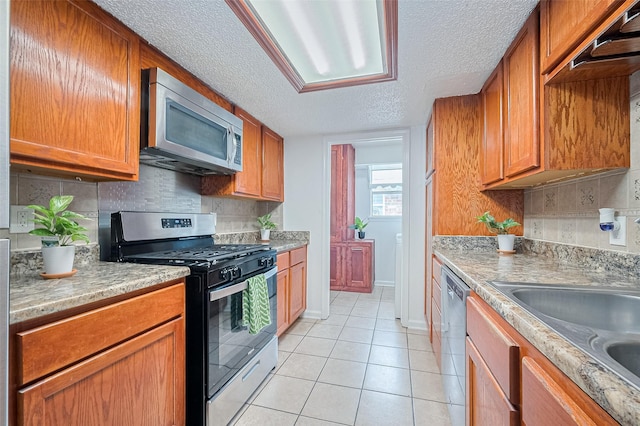 511 Walston Ln, Houston, TX 77060 - kitchen featuring stainless steel appliances, light tile patterned flooring, a textured ceiling, backsplash, and brown cabinets