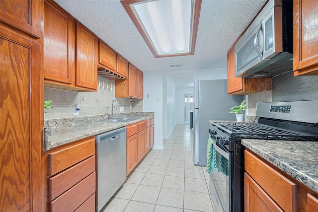 511 Walston Ln, Houston, TX 77060 - kitchen with stainless steel appliances, light tile patterned flooring, tasteful backsplash, a textured ceiling, and brown cabinets