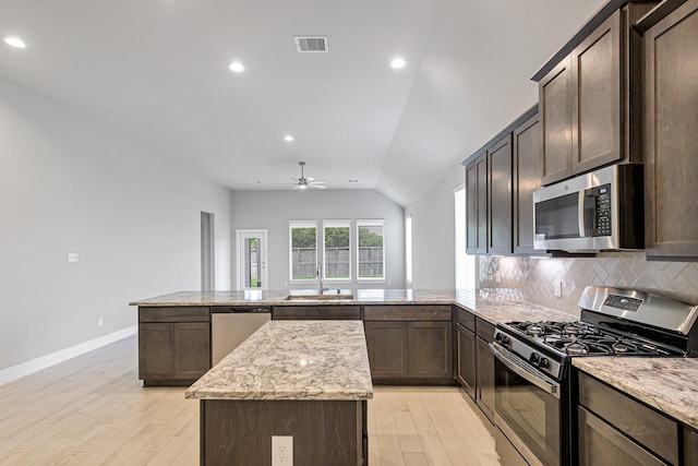 14715 Poplar Lake Trl, Cypress, TX 77429 - kitchen with appliances with stainless steel finishes, light wood-style floors, a peninsula, lofted ceiling, and tasteful backsplash