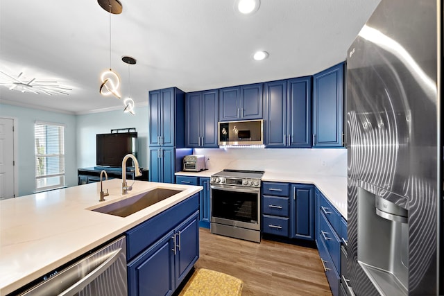 8416 Seawall Blvd Unit 5, Galveston, TX 77554 - kitchen with appliances with stainless steel finishes, blue cabinets, light countertops, hanging light fixtures, and light wood-style floors