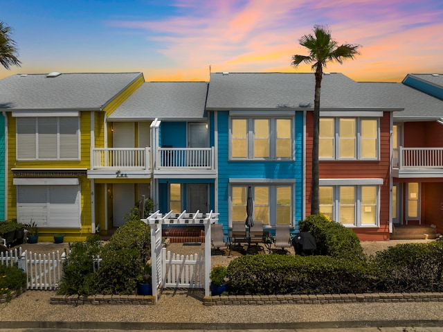 8416 Seawall Blvd Unit 5, Galveston, TX 77554 - back of property at dusk with a balcony, roof with shingles, and a gate