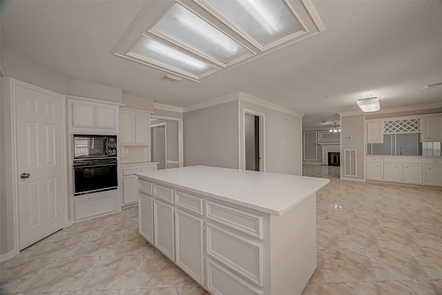 2112 Limrick Dr, Pearland, TX 77581 - kitchen featuring black appliances, a center island, white cabinets, ornamental molding, and light countertops