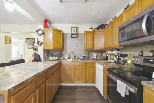 1732 Lynn Ln, Freeport, TX 77541 - kitchen featuring appliances with stainless steel finishes, a peninsula, dark wood finished floors, brown cabinetry, and light countertops