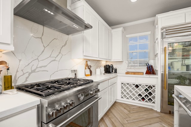 915 Bernard Meadows Dr, East Bernard, TX 77435 - kitchen with wall chimney exhaust hood, premium appliances, white cabinetry, tasteful backsplash, and ornamental molding