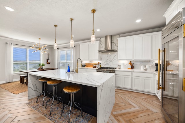 915 Bernard Meadows Dr, East Bernard, TX 77435 - kitchen with wall chimney range hood, appliances with stainless steel finishes, backsplash, a kitchen island with sink, and ornamental molding