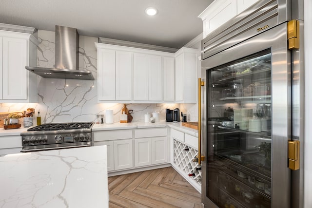 915 Bernard Meadows Dr, East Bernard, TX 77435 - kitchen featuring wall chimney range hood, appliances with stainless steel finishes, white cabinets, decorative backsplash, and light stone counters