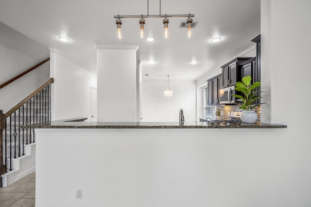 31767 Chapel Rock Ln, Spring, TX 77386 - kitchen featuring dark stone counters, appliances with stainless steel finishes, a peninsula, decorative backsplash, and pendant lighting
