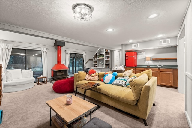 111 Mesa Ct, Conroe, TX 77304 - living area with a textured ceiling, light colored carpet, a wood stove, bar with sink, and recessed lighting