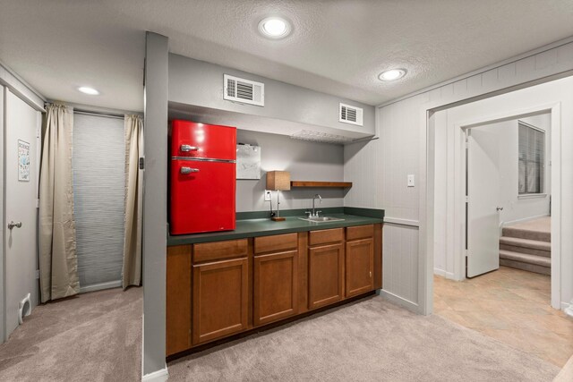 111 Mesa Ct, Conroe, TX 77304 - kitchen featuring brown cabinets, light colored carpet, a textured ceiling, dark countertops, and open shelves