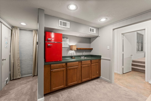 111 Mesa Ct, Conroe, TX 77304 - kitchen featuring brown cabinets, light colored carpet, a textured ceiling, dark countertops, and open shelves