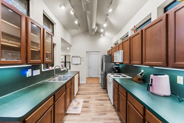 111 Mesa Ct, Conroe, TX 77304 - kitchen featuring white appliances, vaulted ceiling, dark countertops, light wood-style flooring, and glass insert cabinets