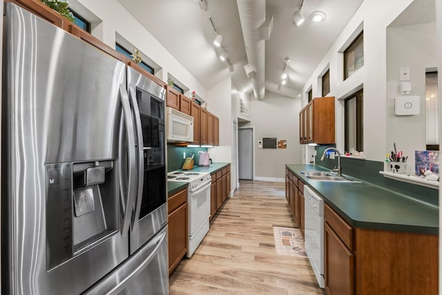 111 Mesa Ct, Conroe, TX 77304 - kitchen with white appliances, dark countertops, brown cabinets, lofted ceiling, and light wood-style flooring