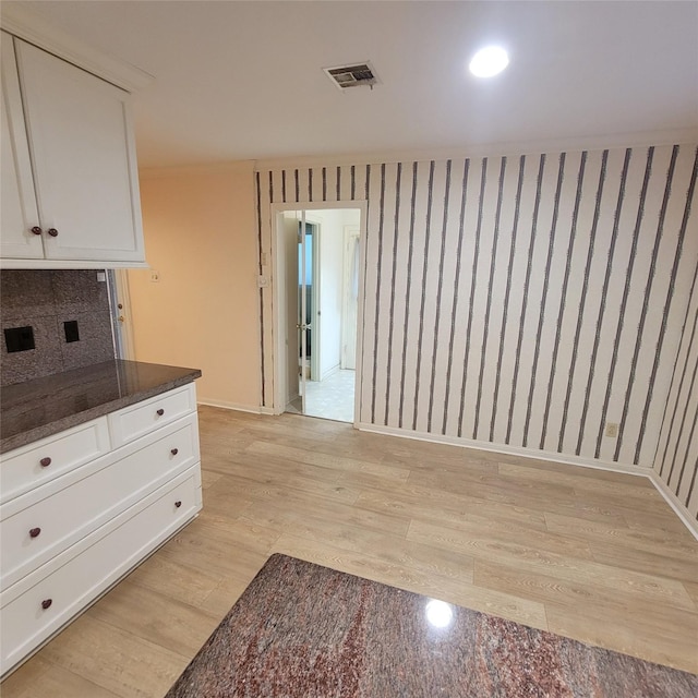 5227 Imogene St, Houston, TX 77096 - kitchen with light wood-type flooring, white cabinetry, tasteful backsplash, and dark stone counters