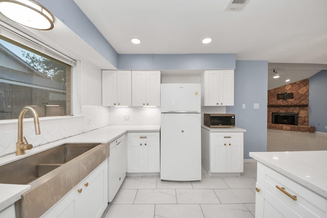 10731 Forest Leaf Dr, Sugar Land, TX 77498 - kitchen featuring white appliances, a fireplace, white cabinets, and backsplash