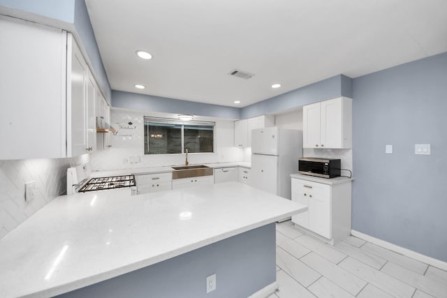 10731 Forest Leaf Dr, Sugar Land, TX 77498 - kitchen featuring white appliances, backsplash, a peninsula, light countertops, and recessed lighting