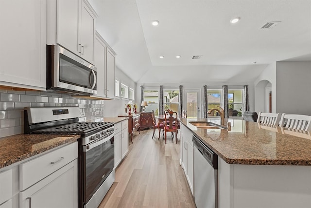 1203 Casal Springs Ct, Crosby, TX 77532 - kitchen with stainless steel appliances, light wood finished floors, a kitchen island with sink, recessed lighting, and decorative backsplash