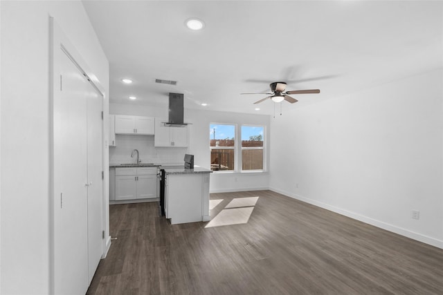 7613 Shotwell St, Houston, TX 77016 - kitchen featuring wall chimney exhaust hood, white cabinets, ceiling fan, recessed lighting, and dark wood-style floors