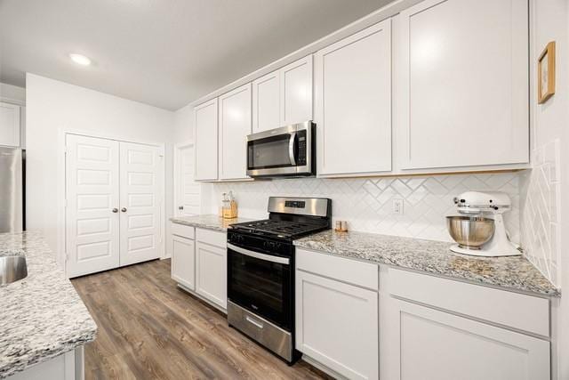 23242 Spring Genesis Ln, Katy, TX 77493 - kitchen featuring appliances with stainless steel finishes, white cabinets, backsplash, and dark wood-style floors