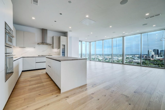 1711 Allen Pkwy Unit 2106, Houston, TX 77019 - kitchen with wall chimney range hood, modern cabinets, backsplash, a wall of windows, and a center island