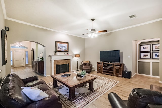 13330 Via Torre De Pisa Ln, Cypress, TX 77429 - living room featuring arched walkways, ceiling fan, light wood finished floors, ornamental molding, and a tiled fireplace
